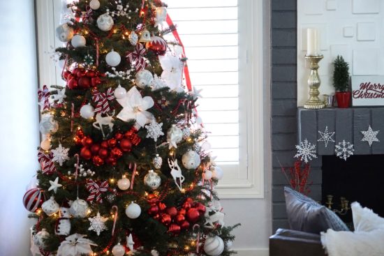 Two brothers are helping to decorate the Christmas tree with red