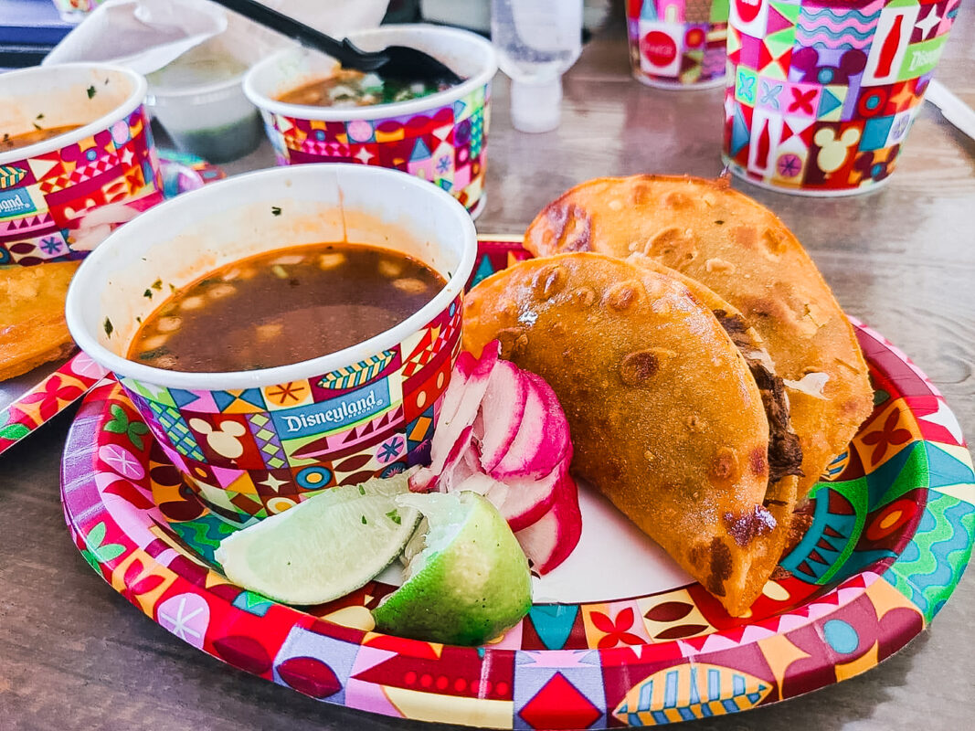 Quessabirria tacos from Disneyland on a plate with limes, radishes, and dipping sauce