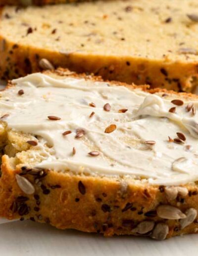 Close up image of the keto seed bread slice with cream cheese on the top.
