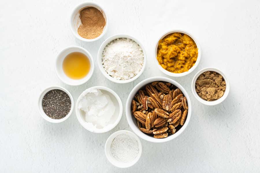 Ingredients required for the pumpkin muffins laid out on a white surface.