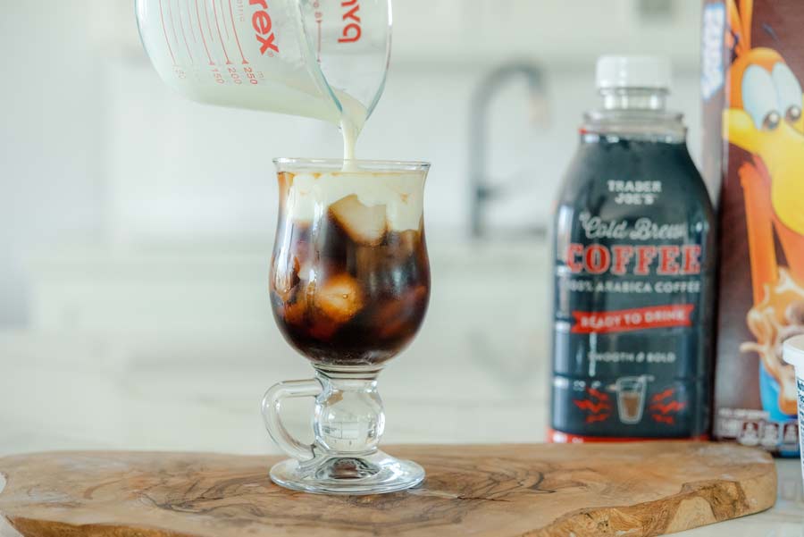 pouring sweet cream cheese topping over cold brew coffee