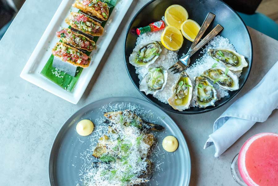 oysters, grilled artichokes and ahi tacos on a table