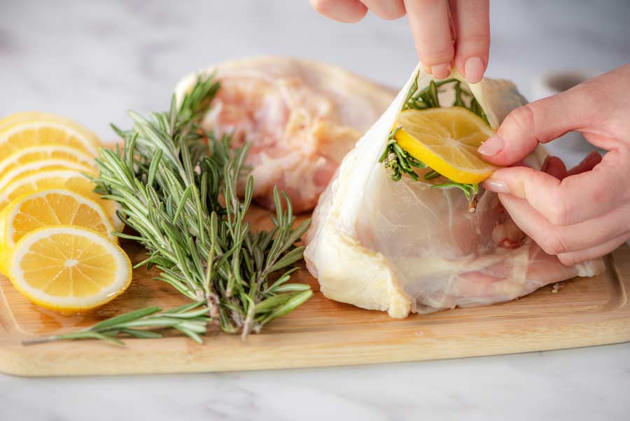 placing lemon and rosemary under skin of chicken bnreast